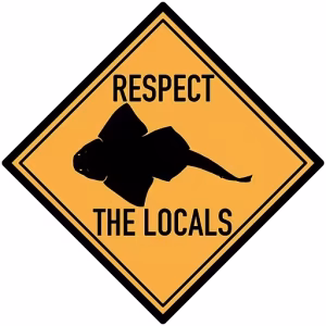 A yellow sign with an angelshark saying respect the locals for the respectful tone.