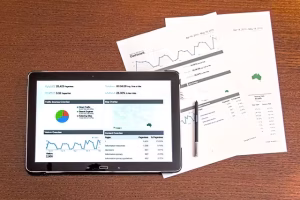 A tablet with data and data analysis paperwork.