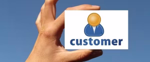 A hand holding a card with customer on it with a blue background.