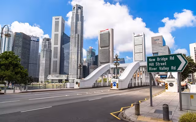A road in singapore with tall buildings in the background.